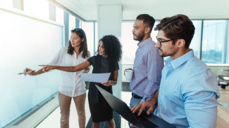 Group of people discussing beside a whiteboard